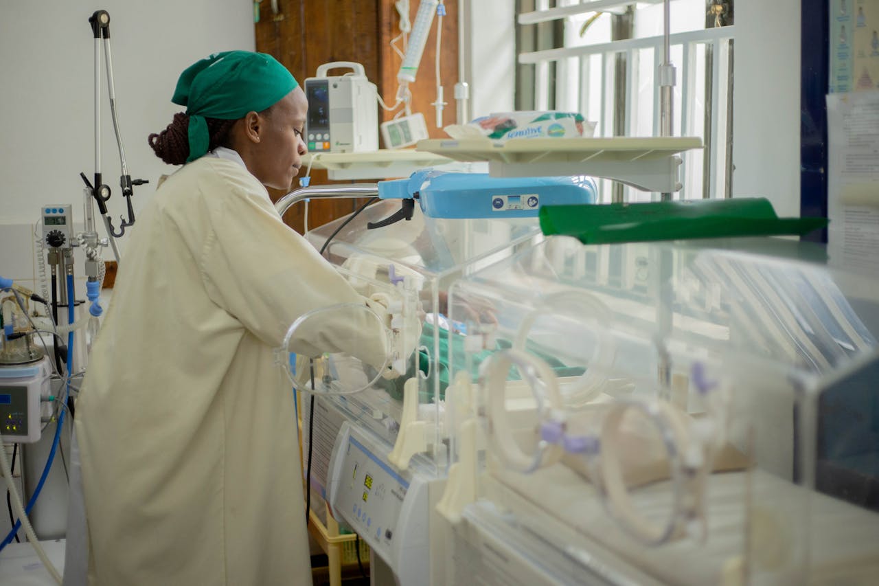 Doctor attending to newborns in an incubator in a hospital neonatal unit.