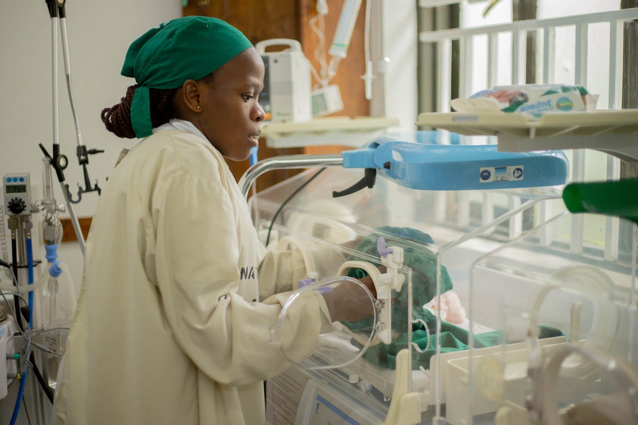 A nurse tends to a newborn in an incubator, ensuring health and safety in a hospital setting.