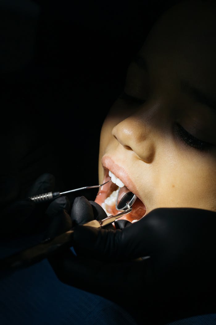 Close-up of a child undergoing a dental checkup with tools in a clinic setting.
